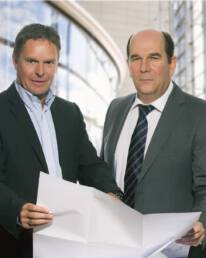 Abbildung der Gesch&auml;ftsf&uuml;hrer von GM Umwelt- und Verkehrstechnik GmbH & Co. KG. Beide Personen halten einen Bauplan in den H&auml;nden.