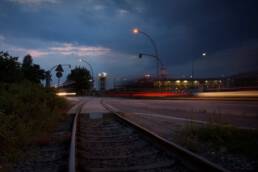 Gleistragplatte aus Beton, eingebaut in einem Bahnübergang. Nachtaufnahme mit erleuchteten Laternen.