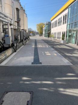 Abbildung einer LKW-Auffangwanne mit mittigem Ablauf, eingebaut im Au&szlig;enbereich eines Industriegel&auml;ndes. Sie f&auml;ngt wassergef&auml;hrdende Fl&uuml;ssigkeiten auf und sorgt f&uuml;r Sicherheit.