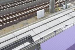 Abbildung einer Gleistragplatte auf Betriebsgelände, zwischen Schienen und Containern